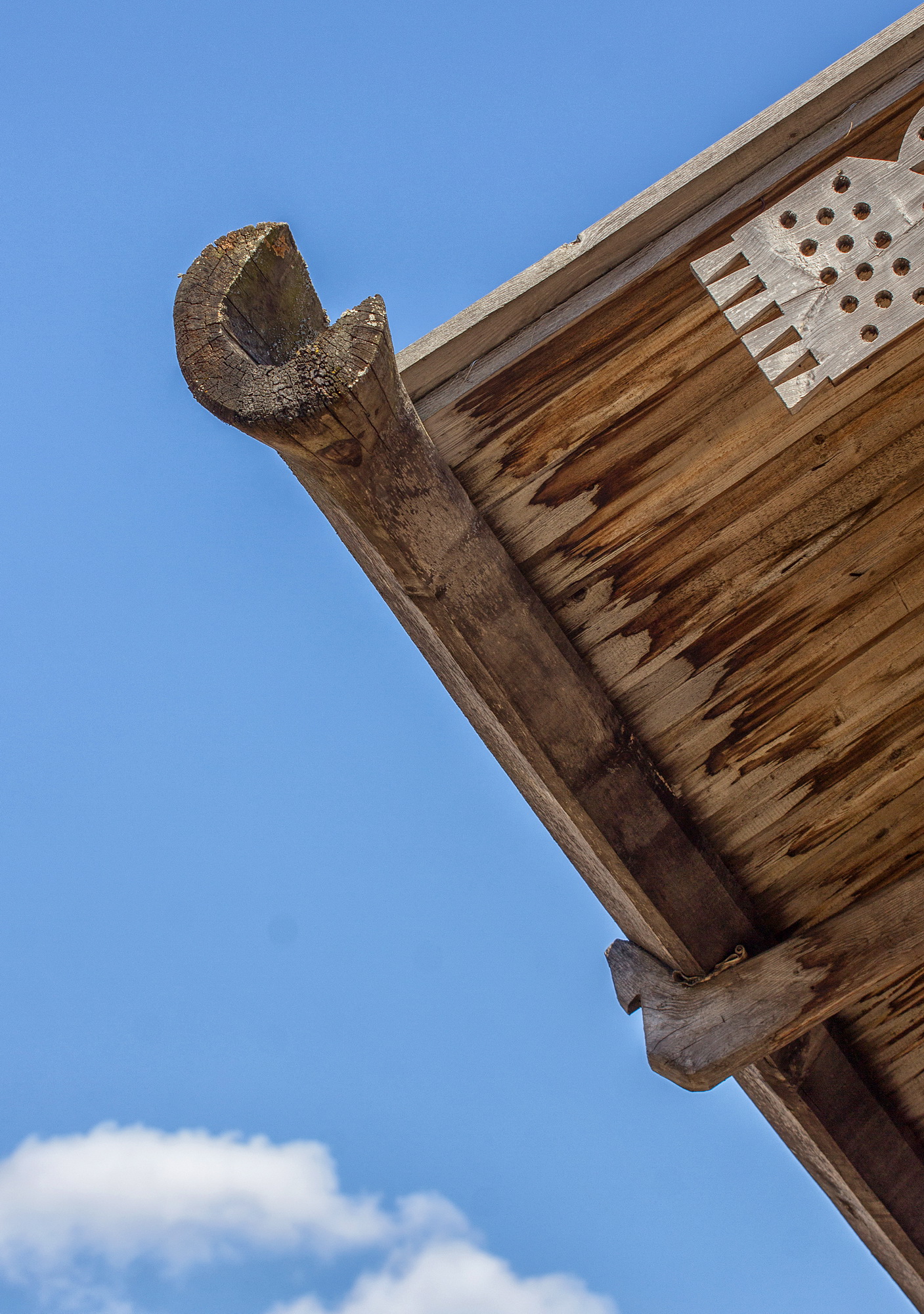 Доска украшенная резьбой закрывающая переход от бревен стены к доскам фронтона избы